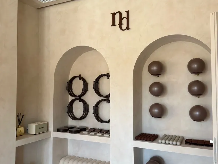 Material de Mat Pilates de Nudhe Studio: magic circles, softballs, bloques y cintas ordenados en hornacinas