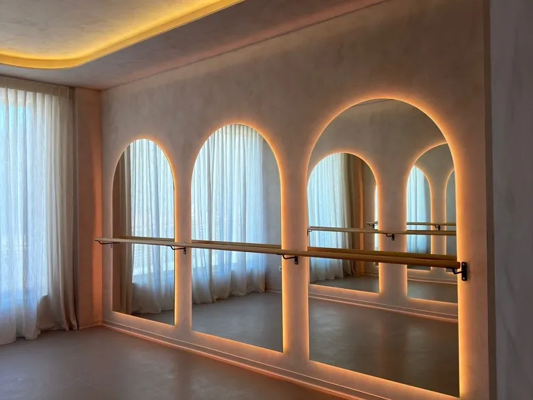 Sala de Barre de Nudhe Studio con barra de ballet y espejos en arco retroiluminados